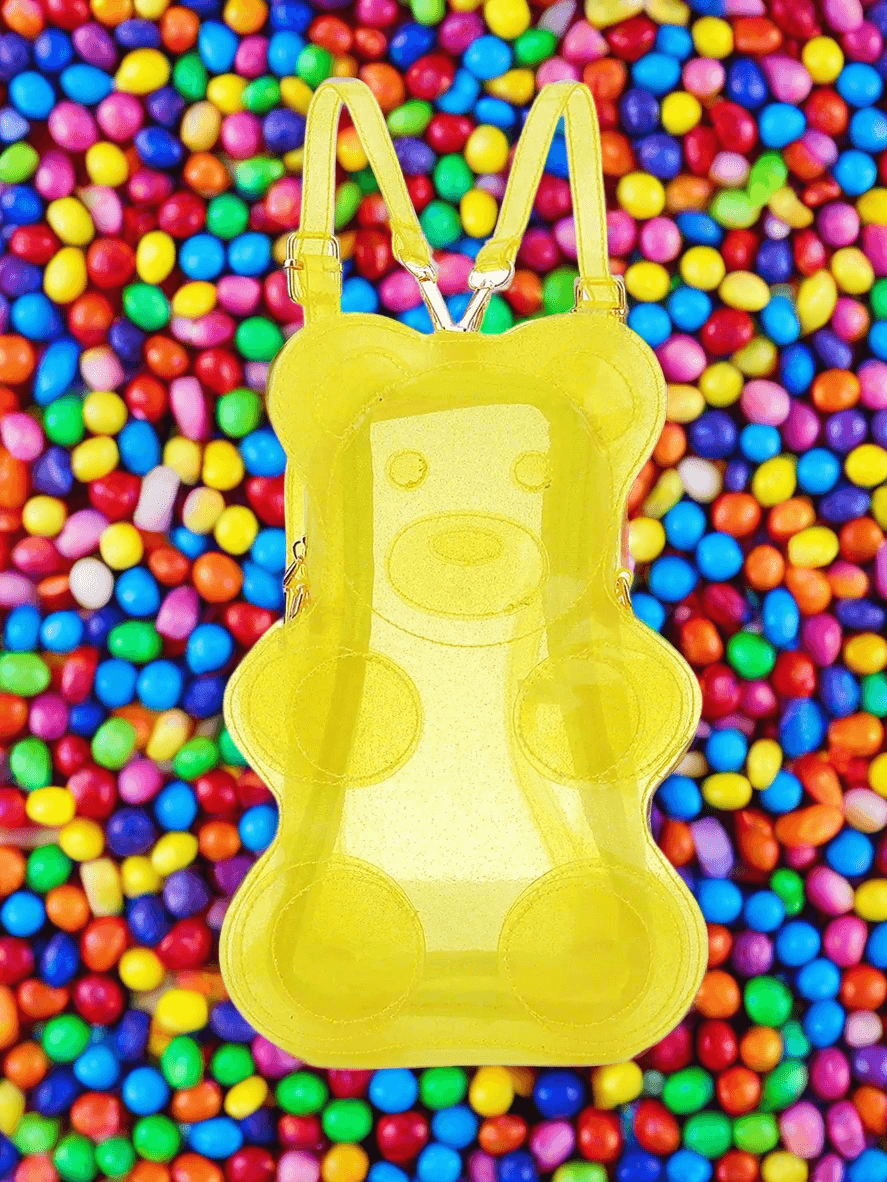 Yellow transparent 🌟🎒 gummy bear backpack with adjustable straps, set against a vibrant, colorful candy background.